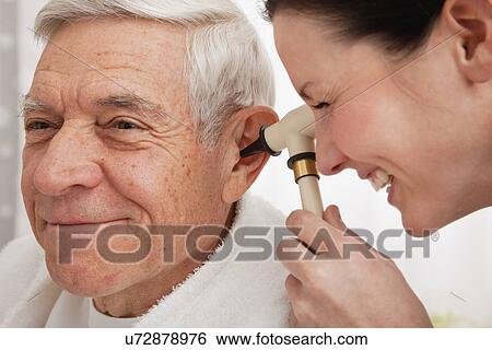 Stock Photograph - Doctor examining senior patient's ear. Fotosearch