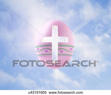 Stock Photography - Easter egg with cross against sky, digital composite. Fotosearch
