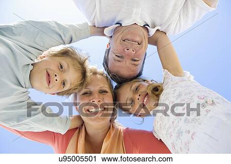 Stock Image - Family including boy and girl (8-9) in huddle, portrait. Fotosearch