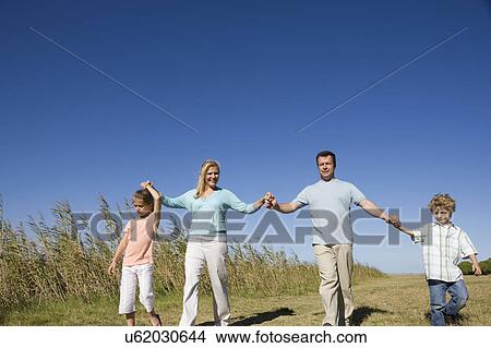 Picture - Family including boy and girl (8-9) walking in field. Fotosearch