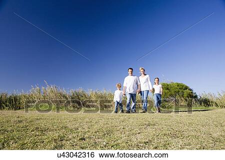 Family including boy and girl (8-9) walking across grassy field View Large Photo Image Stock Photograph - Family including boy and girl (8-9) walking across grassy field. Fotosearch
