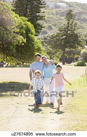 Stock Photography - Family including boy and girl (8-9) walking in park. Fotosearch