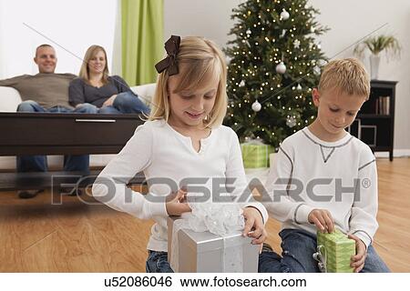 Stock Photograph - Family with boy and girl (6-7, 8-9) celebrating christmas. Fotosearch