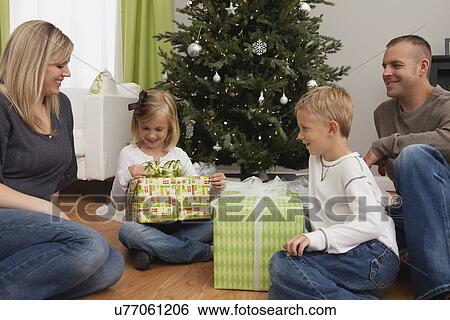 Stock Photograph - Family with boy and girl (6-7, 8-9) celebrating christmas. Fotosearch