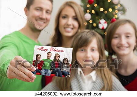 Family with two children (8-9, 10-11) showing Christmas card View Large Photo Image Stock Image - Family with two children (8-9, 10-11) showing Christmas card. Fotosearch
