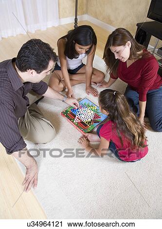 Stock Image - Family with two girls (8-9, 12-13) playing chinese checkers in living room. Fotosearch