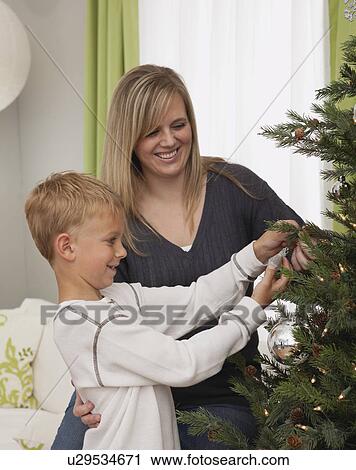 Stock Image - Father and daughter (6-7) decorating christmas tree. Fotosearch