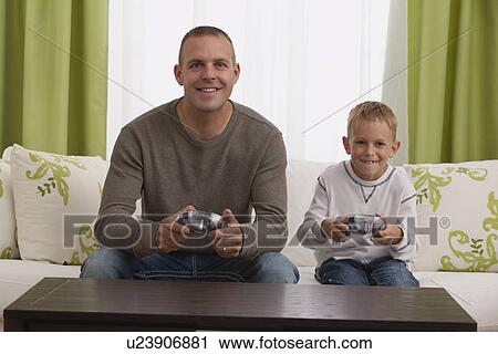 Stock Image - Father and son (8-9) playing computer games. Fotosearch