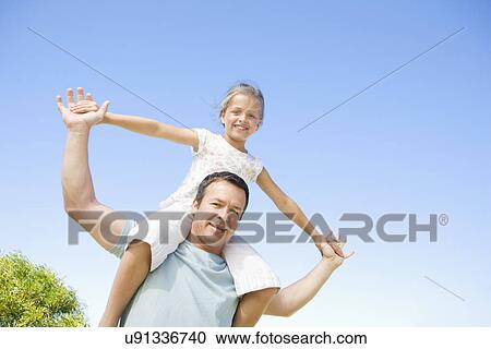 Stock Image - Father carrying daughter (8-9) on shoulders. Fotosearch