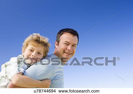 Father carrying son (8-9) on shoulders, portrait View Large Photo Image Picture - Father carrying son (8-9) on shoulders, portrait. Fotosearch