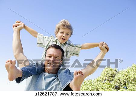 Father carrying son (8-9) on shoulders View Large Photo Image Stock Photo - Father carrying son (8-9) on shoulders. Fotosearch