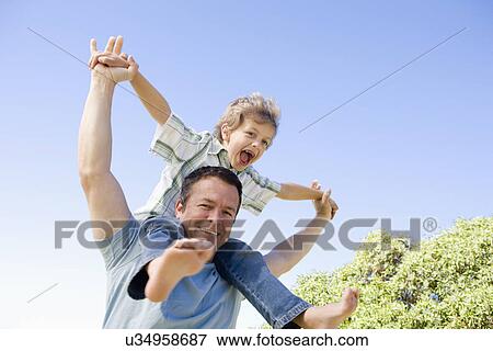 Father carrying son (8-9) on shoulders View Large Photo Image Stock Photo - Father carrying son (8-9) on shoulders. Fotosearch