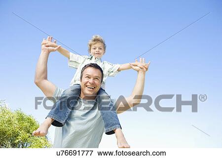 Father carrying son (8-9) on shoulders View Large Photo Image Stock Photo - Father carrying son (8-9) on shoulders. Fotosearch