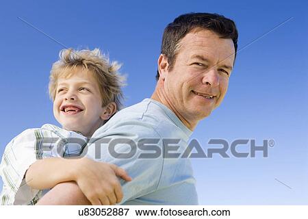 Father carrying son (8-9) on shoulders View Large Photo Image Stock Photo - Father carrying son (8-9) on shoulders. Fotosearch