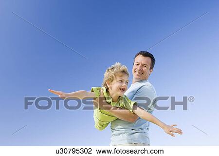 Father holding son (8-9) in air View Large Photo Image Stock Image - Father holding son (8-9) in air. Fotosearch