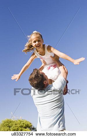 Picture - Father tossing daughter (8-9) in air. Fotosearch
