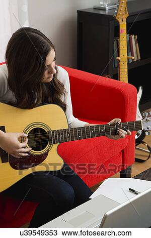Stock Image - Female composer playing guitar. Fotosearch