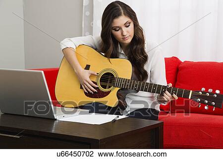 Stock Image - Female composer playing guitar. Fotosearch
