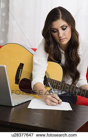 Stock Photo - Female composer playing guitar. Fotosearch
