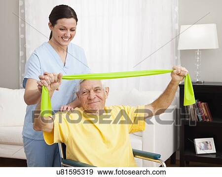 Stock Photo - Female nurse assisting senior man exercising in retirement home. Fotosearch