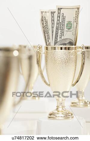 Stock Image - Four gold trophies and banknotes. Fotosearch