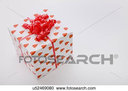 Stock Image - Gift wrapped in heart pattern paper and red ribbon. Fotosearch