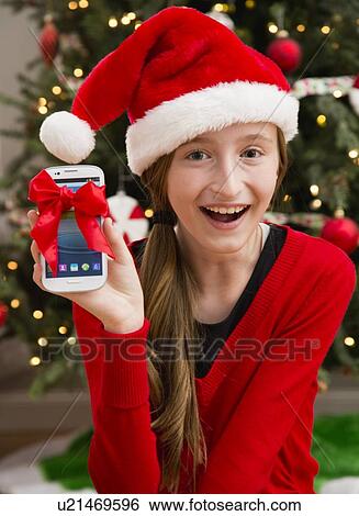 Stock Photograph - Girl (10-11) enjoying her Christmas present. Fotosearch