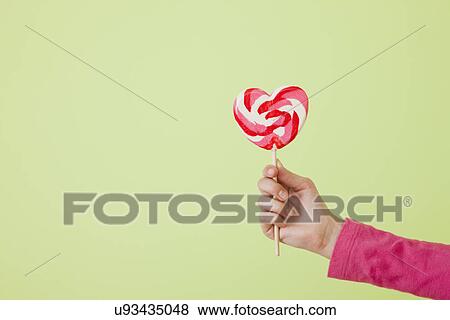 Girl (10-11) holding heart shaped lollipop View Large Photo Image Stock Photo - Girl (10-11) holding heart shaped lollipop. Fotosearch