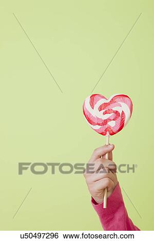Girl (10-11) holding heart shaped lollipop View Large Photo Image Stock Photograph - Girl (10-11) holding heart shaped lollipop. Fotosearch