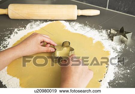 Stock Photo - Girl (12-13) cutting cookie. Fotosearch