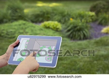 Stock Photo - Girl (12-13) holding digital tablet with garden plan. Fotosearch