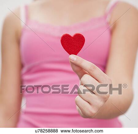 Stock Photo - Girl (12-13) holding little red heart. Fotosearch