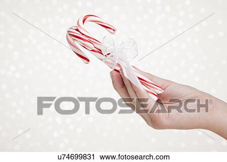 Girl (12-13) holding tied up peppermint candy canes on sparkled background View Large Photo Image Stock Image - Girl (12-13) holding tied up peppermint candy canes on sparkled background. Fotosearch