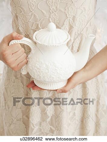 Stock Image - Girl (2-13) holding white teapot. Fotosearch