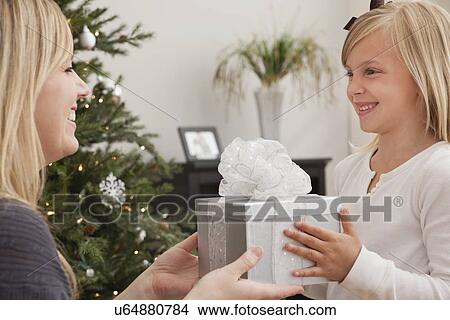 Girl (6-7) receiving christmas present from mother View Large Photo Image Picture - Girl (6-7) receiving christmas present from mother. Fotosearch