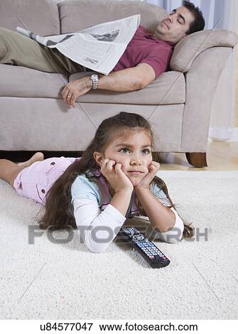 Girl (6-7) watching television, father with newspaper sleeping on sofa in background View Large Photo Image Stock Photo - Girl (6-7) watching television, father with newspaper sleeping on sofa in background. Fotosearch