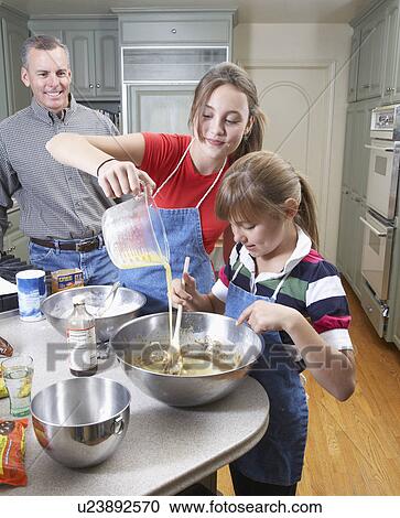 Stock Image - Girls baking with father in kitchen. Fotosearch