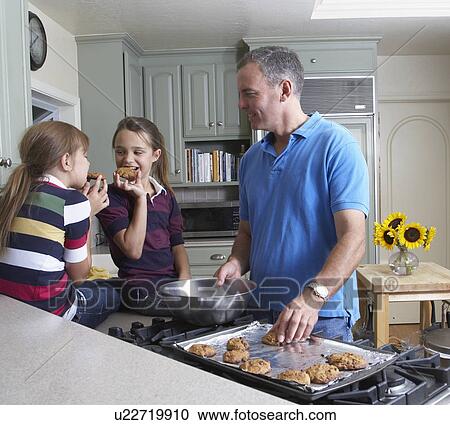 Girls eating cookies with father in kitchen View Large Photo Image Stock Image - Girls eating cookies with father in kitchen. Fotosearch