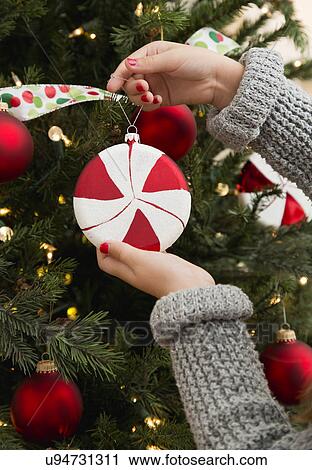 Stock Image - Girl's hands (8-9) decorating Christmas tree. Fotosearch