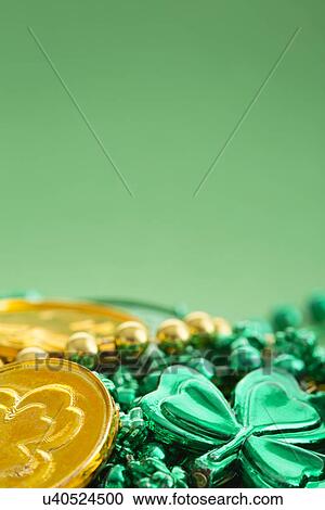 Stock Image - Gold and green coins and shamrock on green. Fotosearch