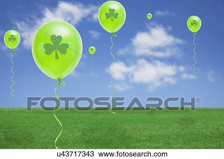 Stock Image - Green balloons flying above green meadow. Fotosearch