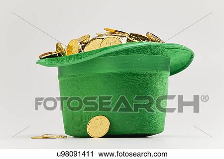 Stock Image - Green hat full of golden coins. Fotosearch