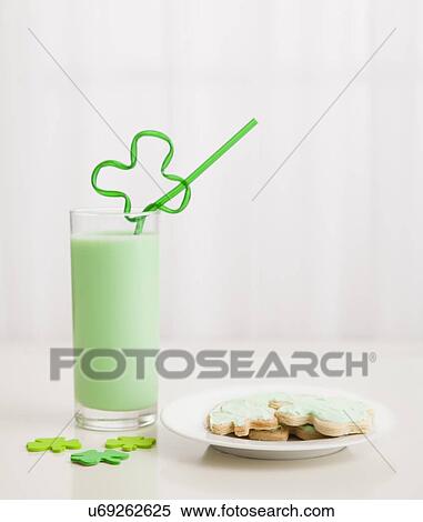 Stock Photography - Green milkshake with shamrock-shaped straw and cookies. Fotosearch