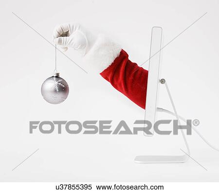 Stock Photography - Hand of Santa Claus holding bauble, coming out of computer monitor. Fotosearch
