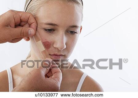 Hands applying adhesive bandage on girl's (12-13) face View Large Photo Image Stock Photo - Hands applying adhesive bandage on girl's (12-13) face. Fotosearch