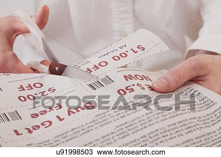 Stock Image - Hands cutting out coupon. Fotosearch