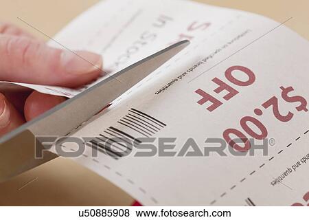 Stock Photo - Hands cutting out coupon. Fotosearch