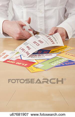 Stock Photo - Hands cutting out coupon. Fotosearch