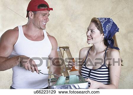 Stock Photo - Happy couple painting room. Fotosearch