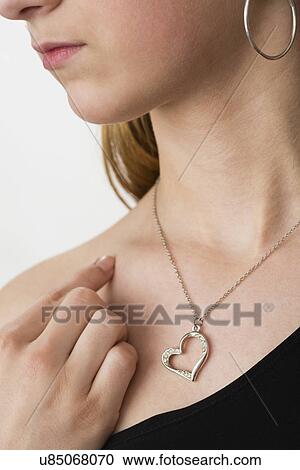 Stock Image - Heart shaped pendant and silver chain on teenager's(14-15) neck. Fotosearch